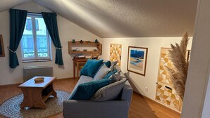 Ein gemütliches Wohnzimmer mit einem grauen Sofa, einem Holztisch und einem kleinen Teppich.