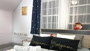 A bedroom with a bed, a nightstand, a window with curtains, a teddy bear, and a box of towels. - Upscale 1BR Loft near UC, DAAP, CCM, Hospital and Zoo w/Parking, 3FL (Cincinnati)
