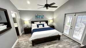 A bedroom with a bed, nightstands, a ceiling fan, and a door leading to a balcony.