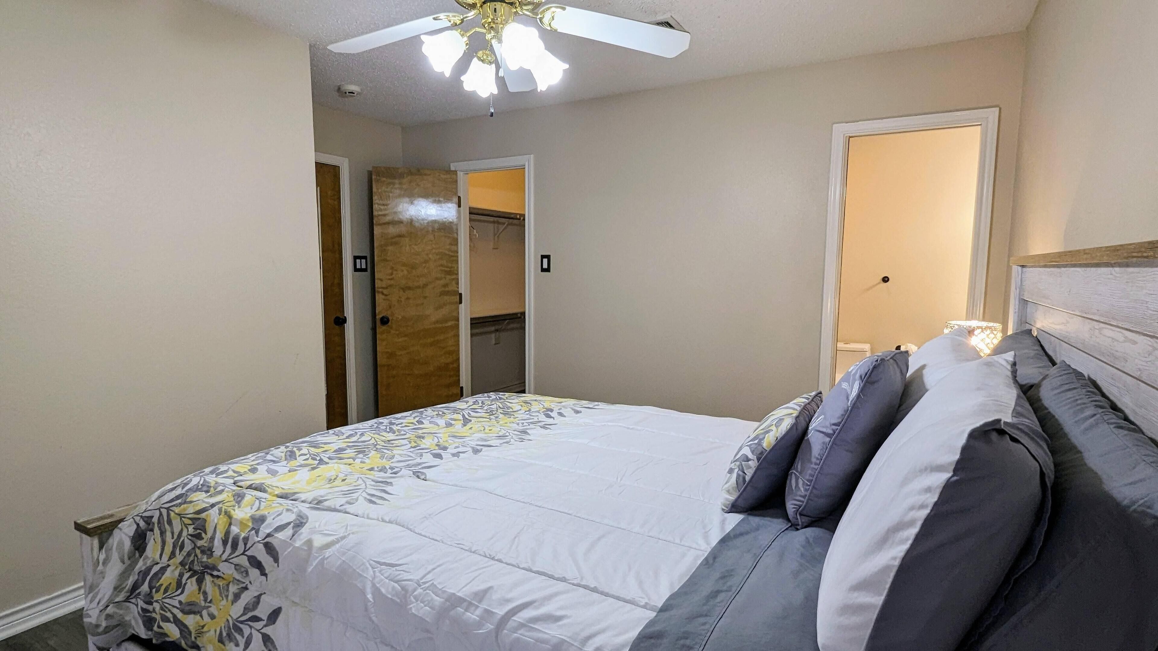 Un dormitorio con cama, ventilador de techo y puerta que da a un armario.