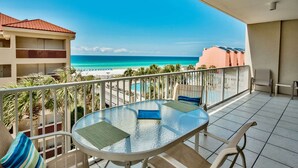 A balcony with a glass table and chairs, overlooking a beach and a pool. - Tides at Tops`l #301- Overlooks the Gulf! (Miramar)