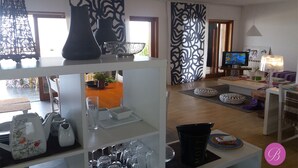 Una sala de estar moderna con televisión, sofá y objetos decorativos en estanterías.