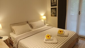Habitación de hotel con cama, dos lámparas de noche, una mesita de noche y ventana con vistas.