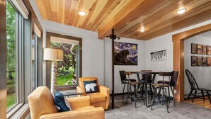 A modern interior with a wooden ceiling, a dining area with black chairs, and a painting of a bear on the wall. - Mountain Harbor Vibrant Vista at Whitefish Lake (Whitefish)