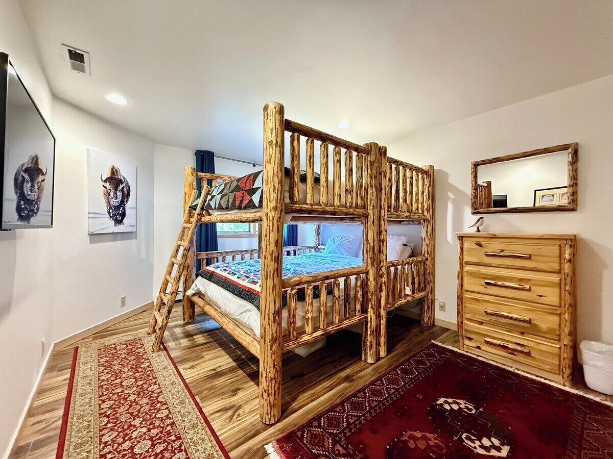 Un lit superposé avec une structure en bois, une commode et un tapis dans une chambre.