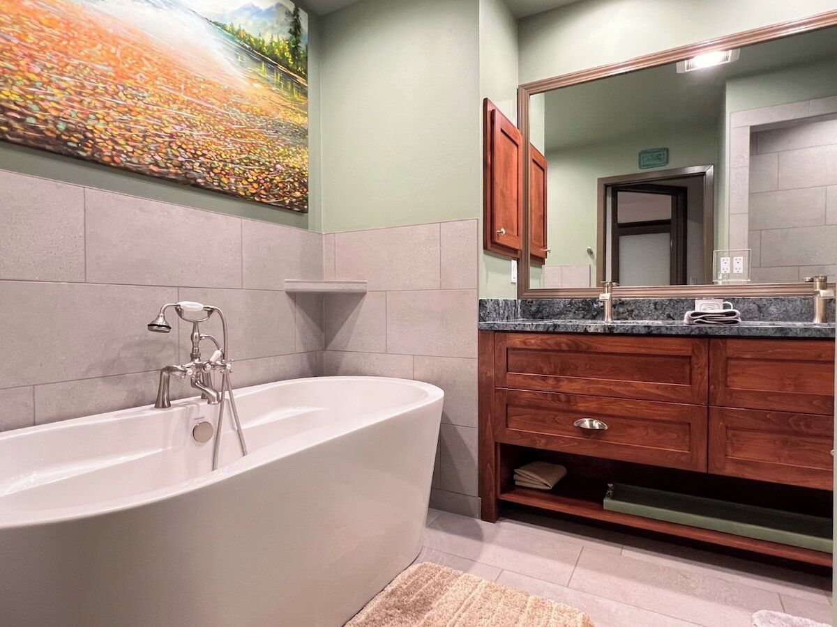 A modern bathroom with a freestanding bathtub, wooden vanity, and a large mirror.