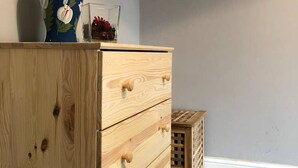 A wooden dresser with drawers, a vase with white flowers, and a framed picture on the wall. - Double bedroom near Heathrow (Hayes)
