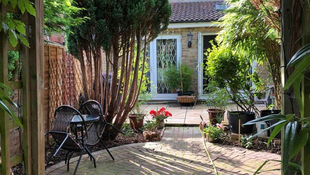 A brick patio with a wooden pergola, a small table, and chairs. - Double bedroom near Heathrow (Hayes)