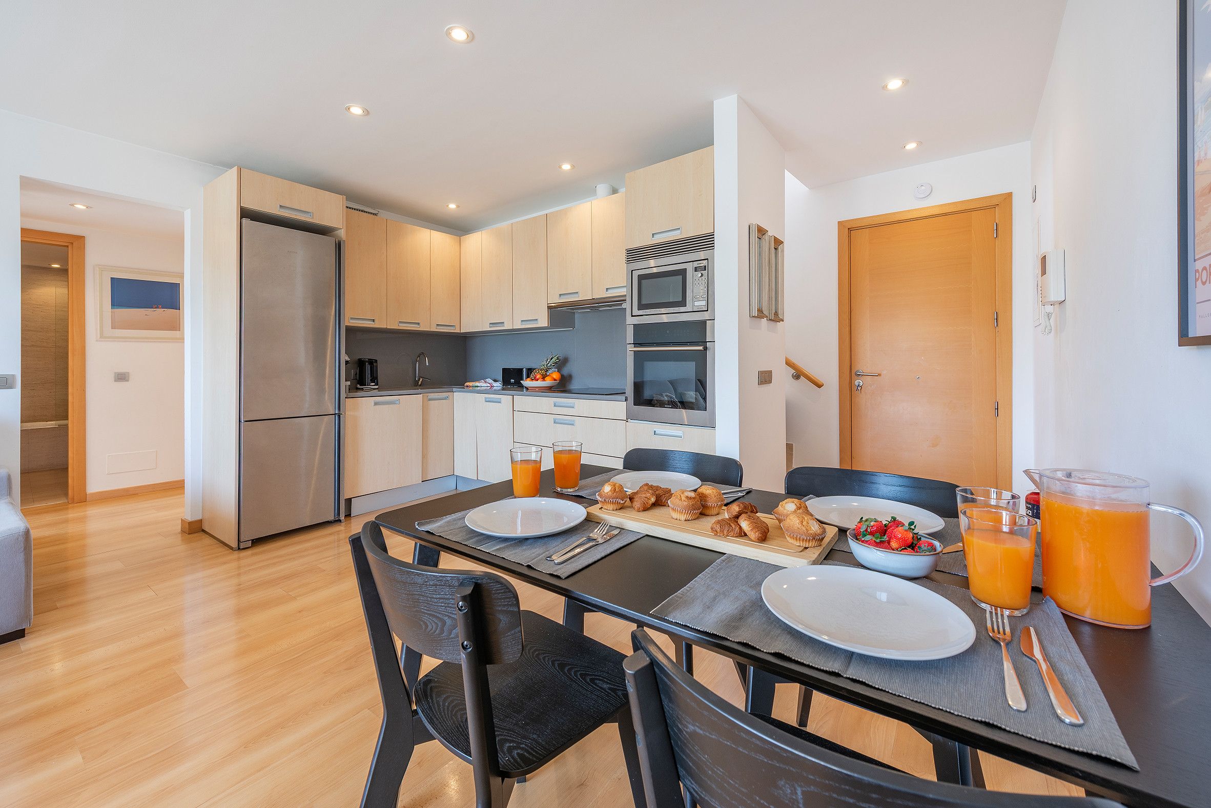 A modern kitchen with a dining area, equipped with a refrigerator, microwave, and oven.