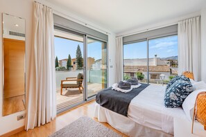 A bedroom with a bed, a chair, and a view of the outside. - Penthouse Rosas with Private Jacuzzi & Pool overlooking the Mountains (Puerto Pollensa)