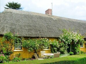 Charming cottage with a lush garden and a cozy outdoor dining area.