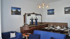 Un comedor con una mesa lista para cuatro personas, un espejo sobre la mesa y dos jarrones con flores en el tocador.