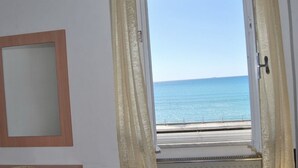 Una habitación con vista al mar a través de una ventana abierta.