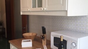 Una cocina con armarios blancos, un microondas, un cuenco de madera y un par de tijeras sobre la encimera.