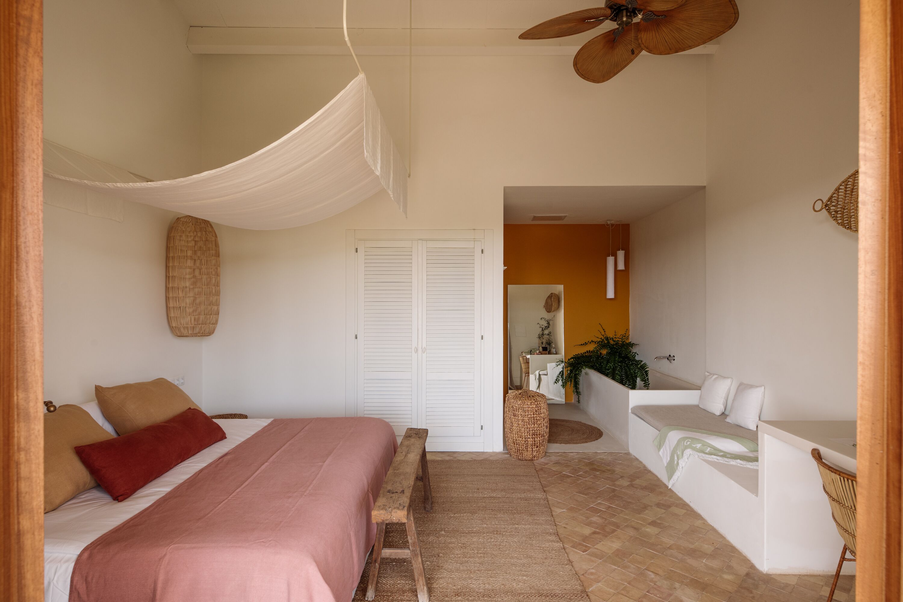 A bedroom with a bed, bench, and a desk area with a chair.