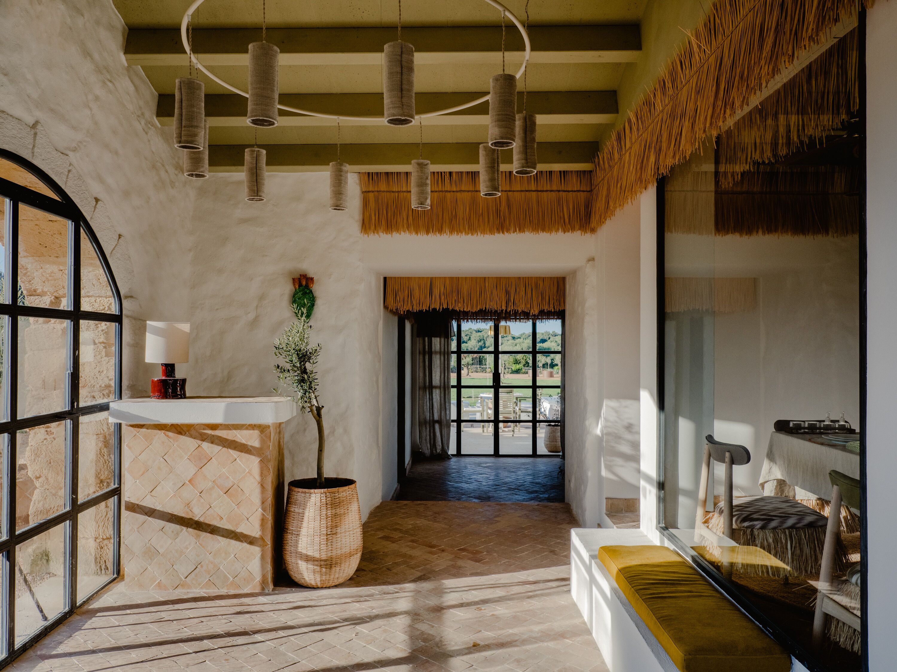 Una habitación con un ventanal amplio, una mesa de recepción y una planta.