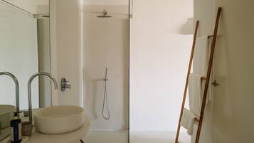 Un baño con un lavamanos grande, dos espejos, una ducha y una escalera de madera.