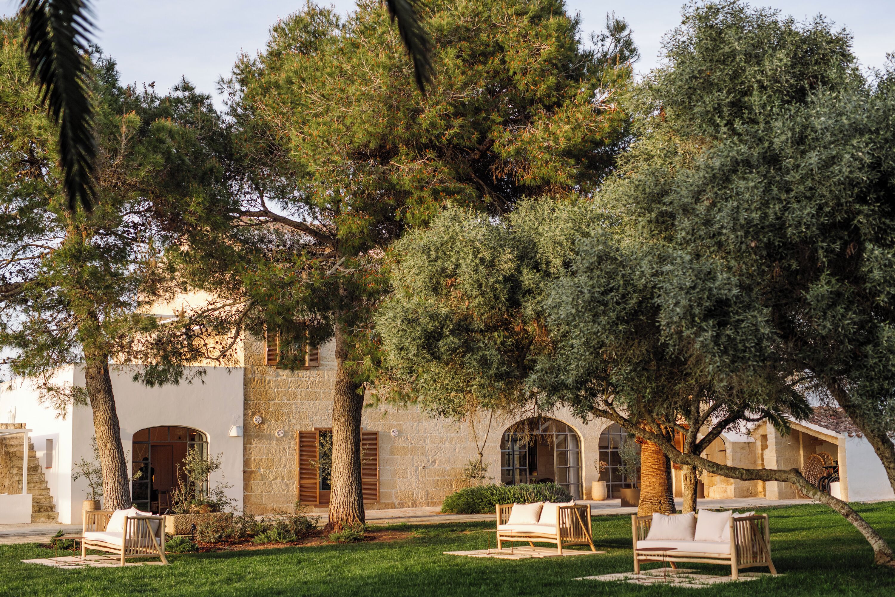 A courtyard with outdoor seating, a stone building, and trees.