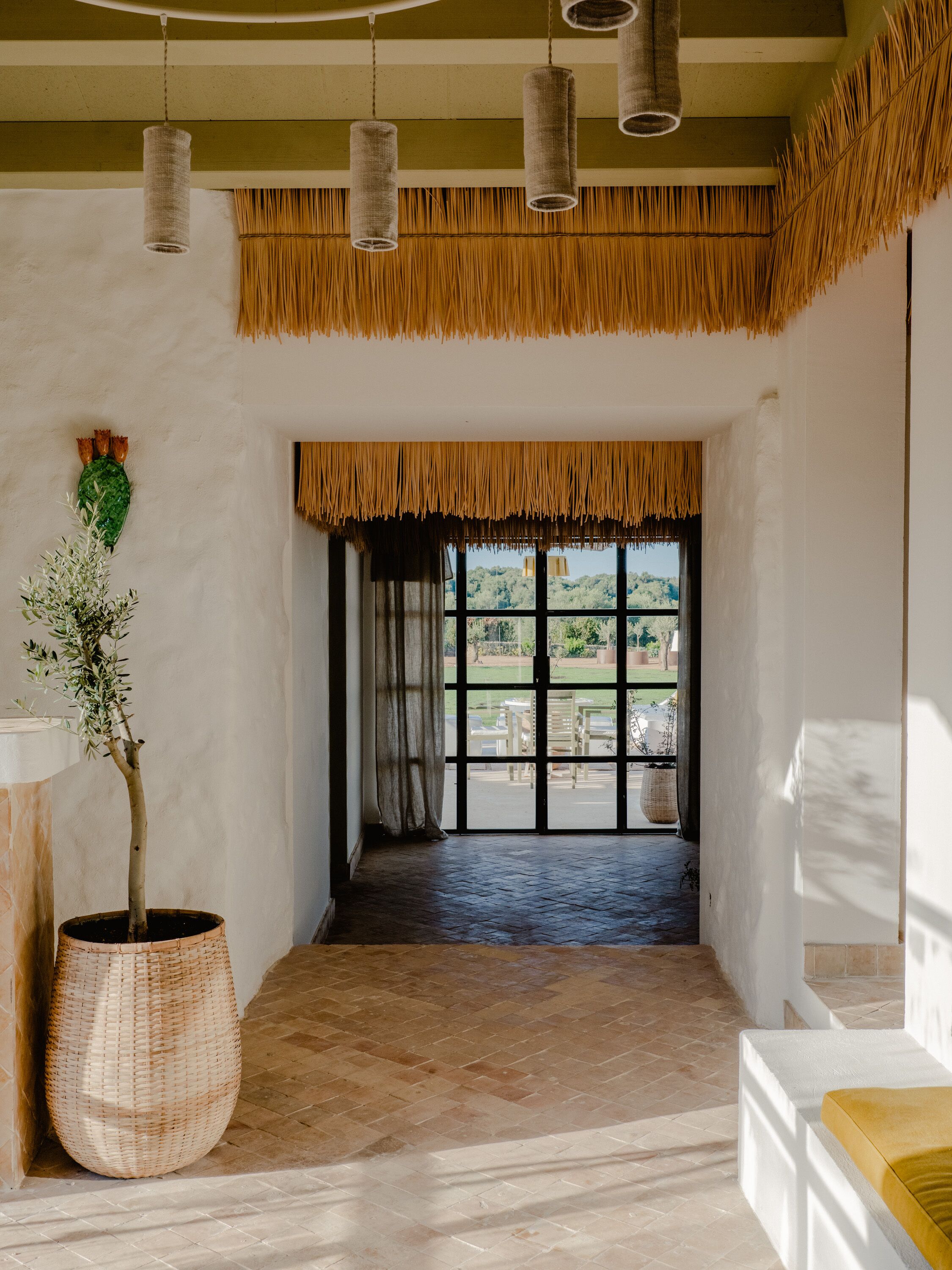 A room with a large window, a potted plant, and hanging light fixtures.