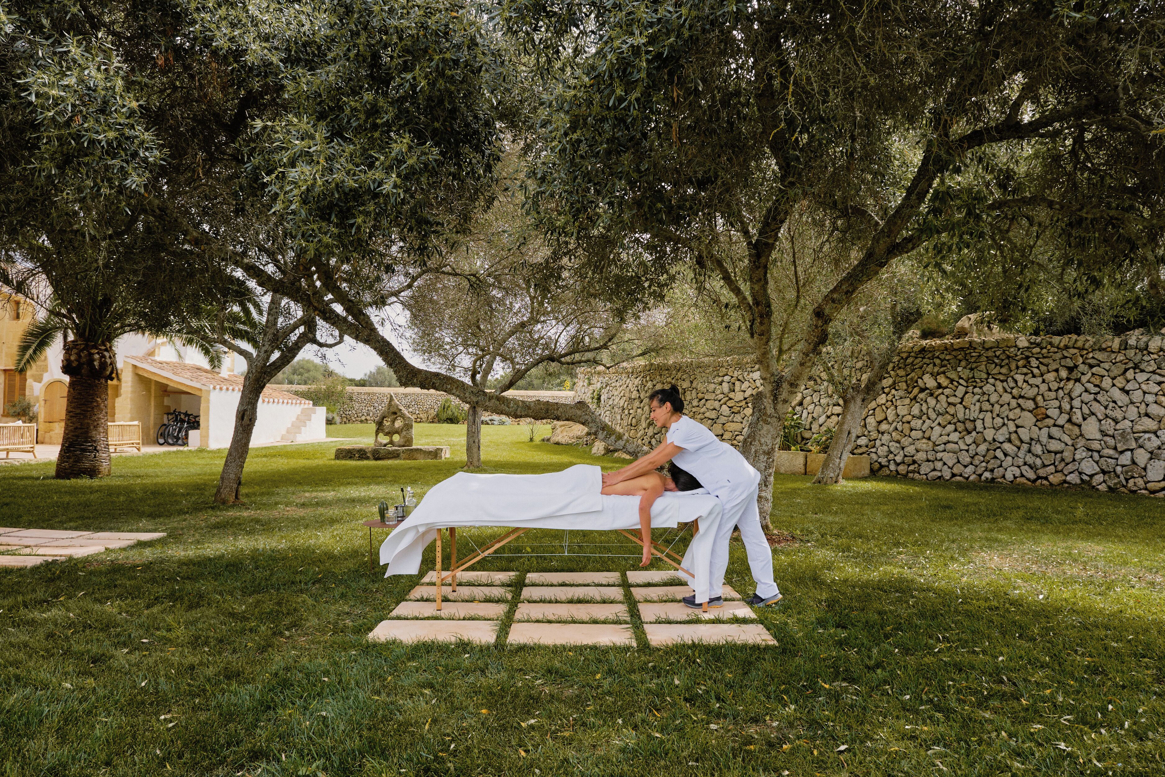 Eine Massage im Garten mit Steinmauer und Bäumen.