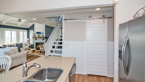 A modern kitchen with a stainless steel refrigerator, a double sink, and a sliding barn-style door leading to a dining area.