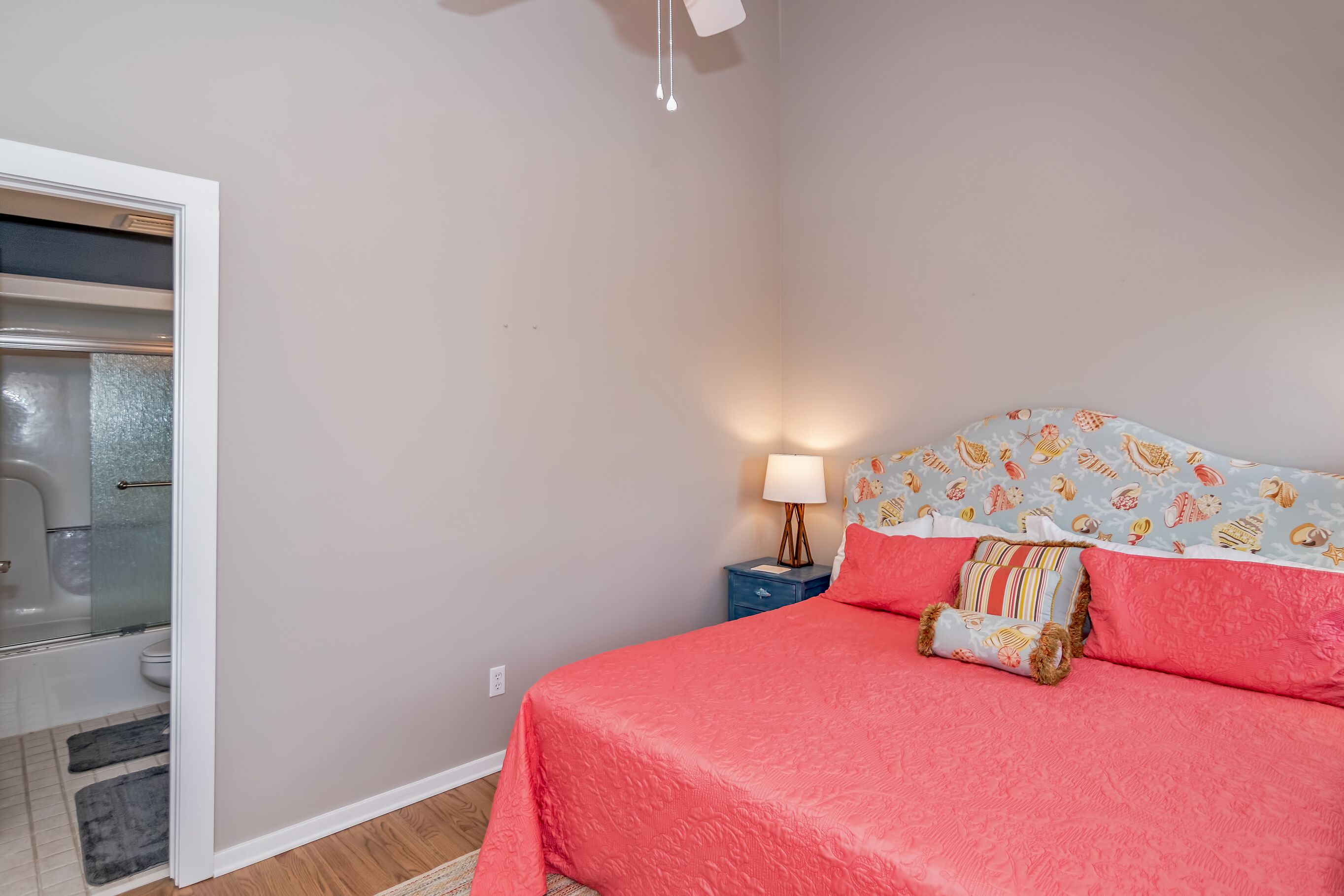 A bedroom with a bed, a nightstand, a lamp, and a patterned headboard.