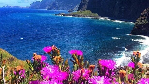 A coastal landscape with cliffs and a clear blue sea.