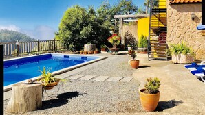 A pool area with a stone wall, potted plants, and a wooden deck.