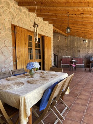 A rustic dining area with a stone wall, wooden doors, and a tiled floor. - Quinta Safari House montains and ocean views (Ribeira Brava, Madeira)