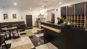 Un'area reception moderna con pavimento a scacchi bianchi e neri, una scrivania reception e un'area salotto con tavoli e sedie.