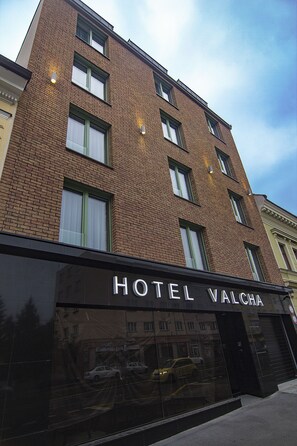 Un hotel con fachada de ladrillo, varias ventanas y un letrero que dice "HOTEL VALCHA".