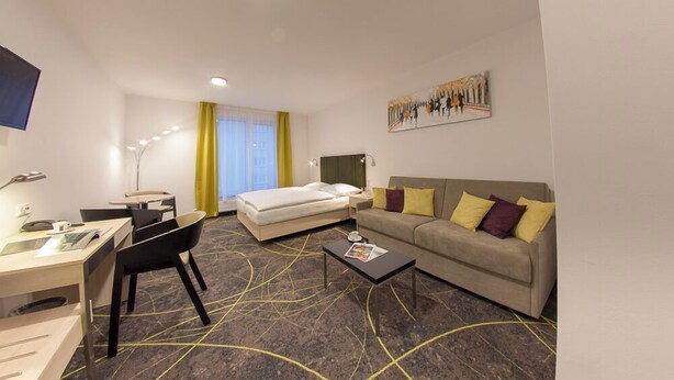 Una camera d'hotel con un letto, un divano, una scrivania e una sedia.