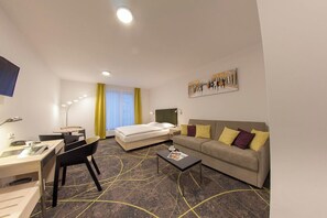 A hotel room with a bed, a sofa, a desk, and a chair.