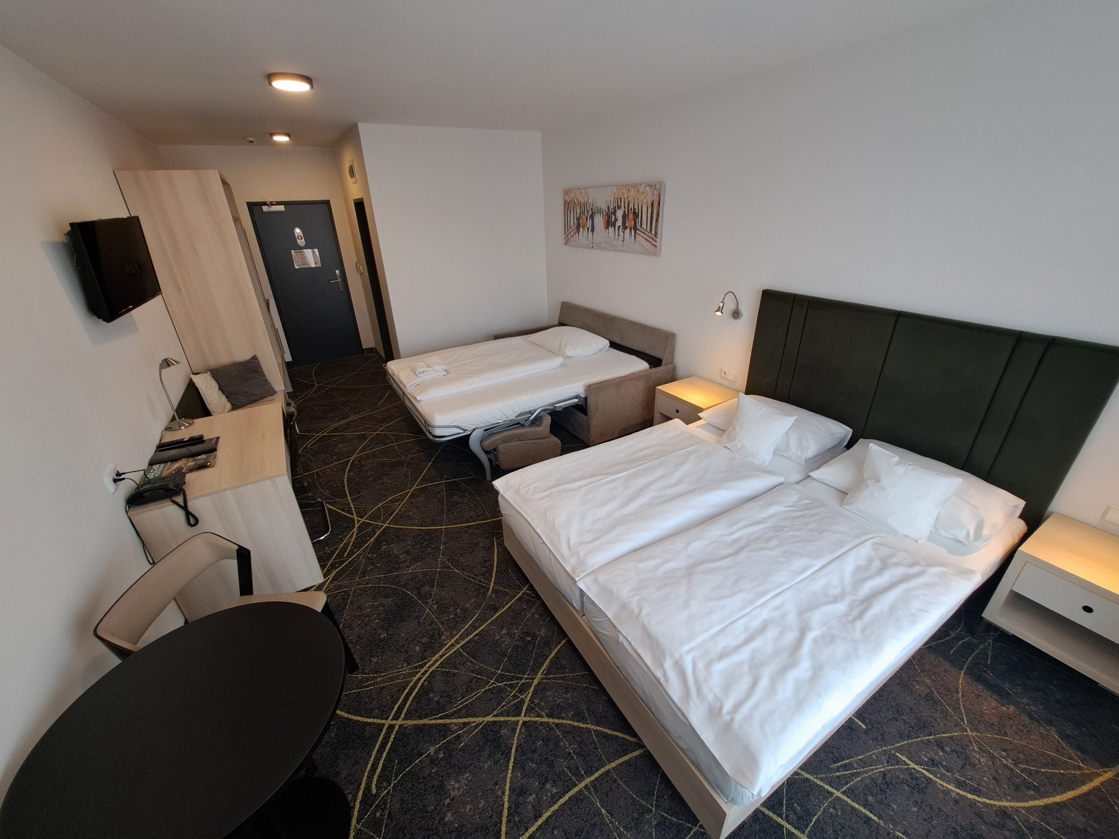 Een hotelkamer met twee bedden, een bureau, een stoel, een televisie en een deur.