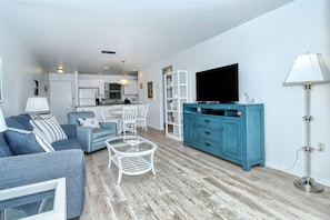 A modern living room with a sofa, coffee table, and a TV on a blue cabinet.