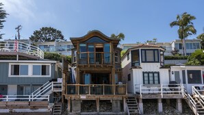 A beachfront property with a multi-level deck, a covered outdoor area, and a staircase leading to the beach. - Whimsical Wave on Miramar Beach | One of a Kind Direct Beachfront Experience! (Santa Barbara)