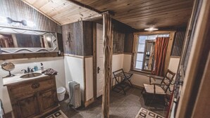 Un baño rústico con tocador de madera, un espejo grande y una ventana con cortinas.