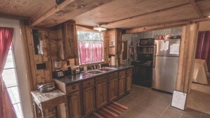Una cocina rústica con gabinetes de madera, un refrigerador de acero inoxidable y un microondas integrado.