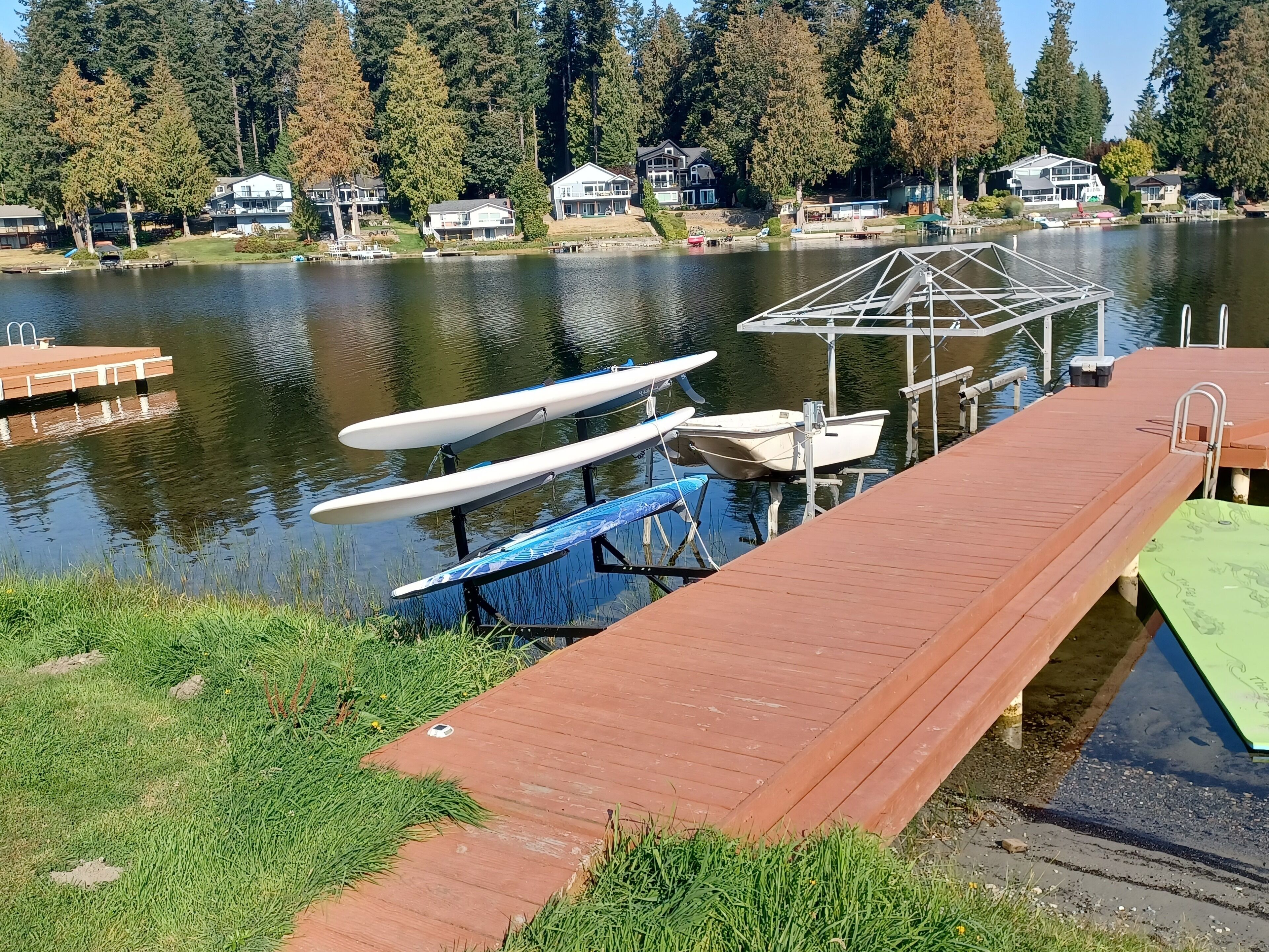 A dock with several boats and a house in the background.