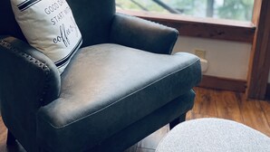 A dark leather armchair with a white pillow that has text on it, positioned near a window with a view of trees. - Panoramic Coeur D'Alene Lake View - 5 Minutes to Town (Coeur D Alene)
