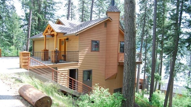 A two-story log cabin with a balcony, surrounded by trees. - Panoramic Coeur D'Alene Lake View - 5 Minutes to Town (Coeur D Alene)