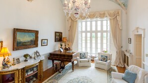 A spacious room with a grand chandelier, a piano, and elegant furniture. - Lisheen Castle, Beautifully Restored, Perfect Central Location for Day Tripping  (Thurles)