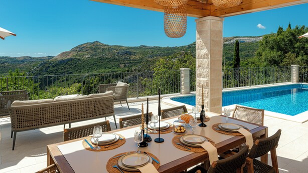 Un espacio de comedor al aire libre con vistas a una montaña y una piscina.
