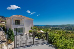 Una casa moderna de dos pisos con techo de tejas, ventanas amplias y vistas a un valle.