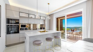 Una cocina moderna con una isla central, taburetes de bar y vistas a un patio con mobiliario exterior.
