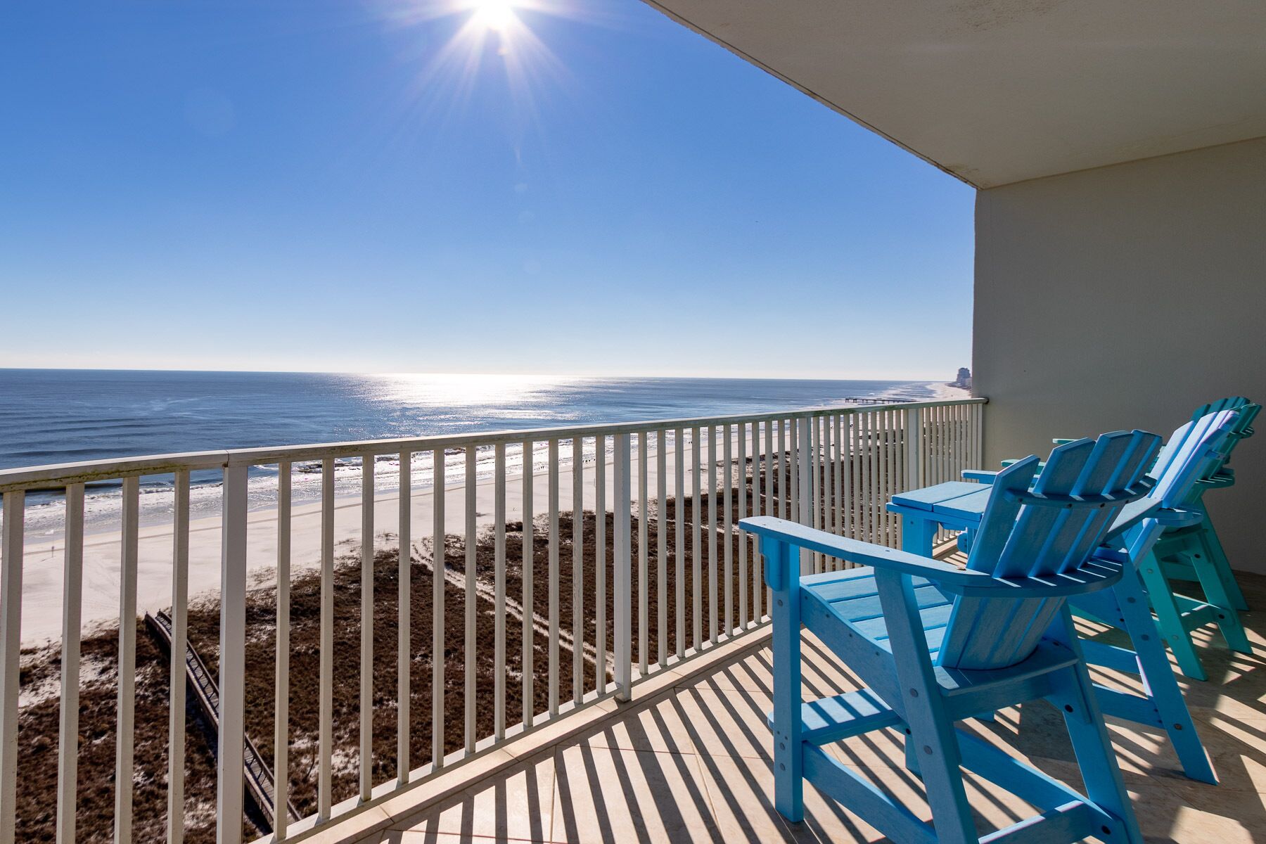 A balcony with a view of the beach and ocean.