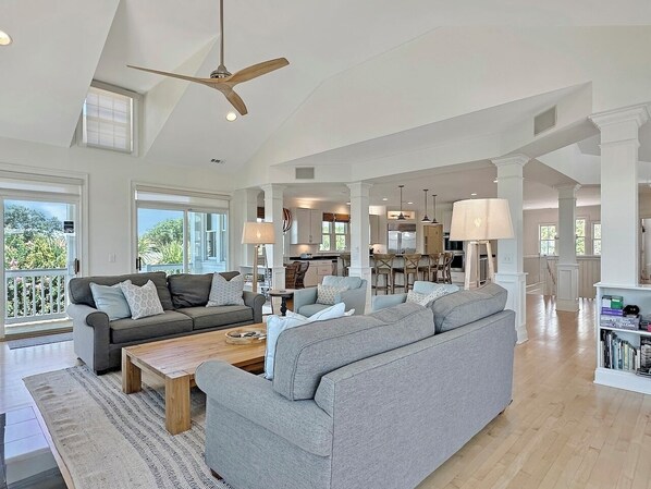A spacious living area with a grey sectional sofa, a wooden coffee table, and a ceiling fan.