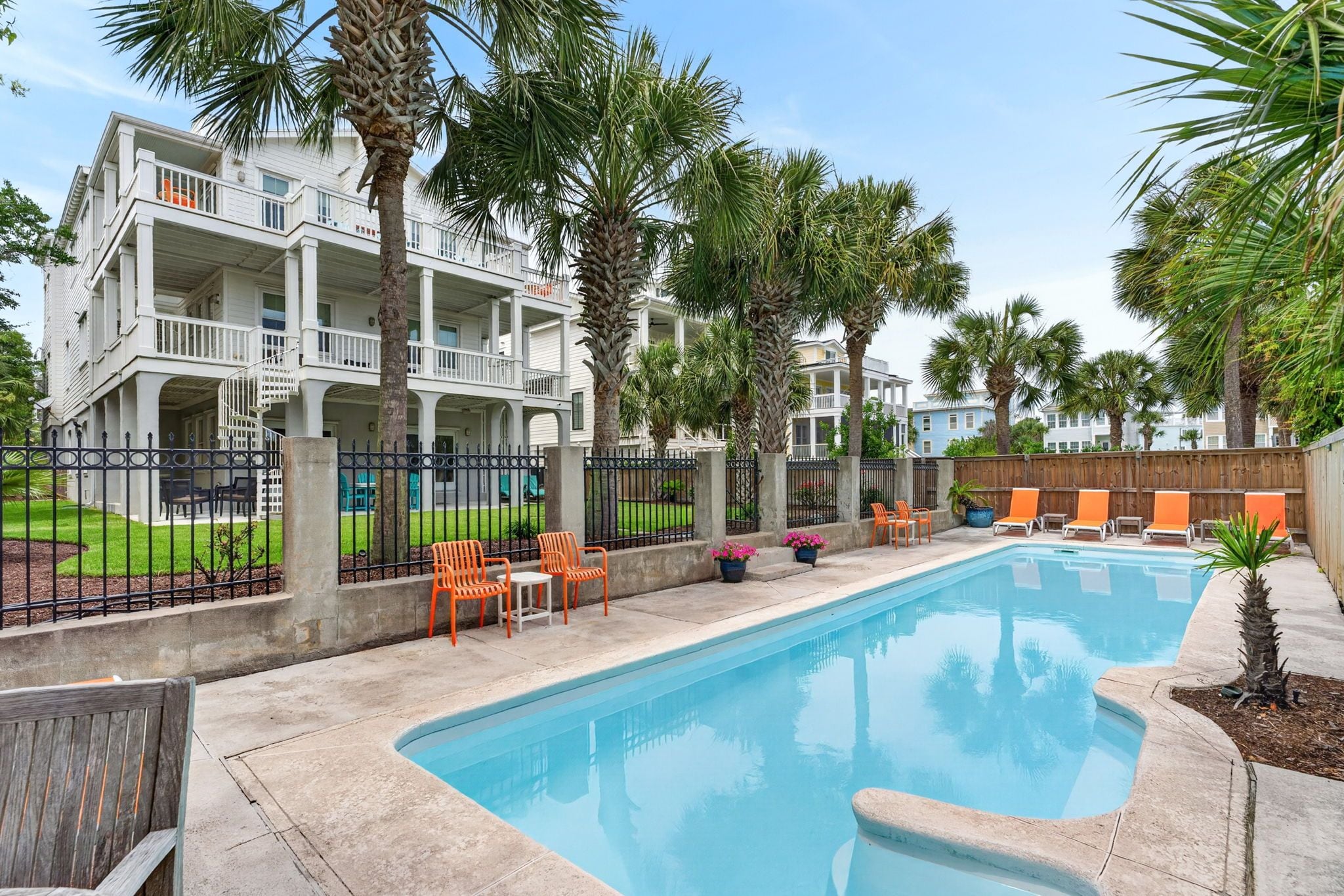 A swimming pool with lounge chairs, a fenced area, and a multi-story building with balconies.