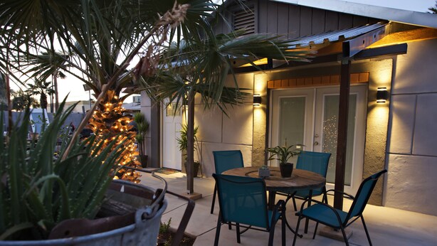 An outdoor patio with a round table and four chairs, surrounded by potted plants and a palm tree. - Private Guesthouse in Central Phx--Beaker Bunker (Phoenix)