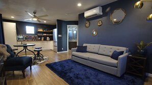 A modern living room with a grey sofa, a blue rug, and a dining area with a table and chairs. - Private Guesthouse in Central Phx--Beaker Bunker (Phoenix)